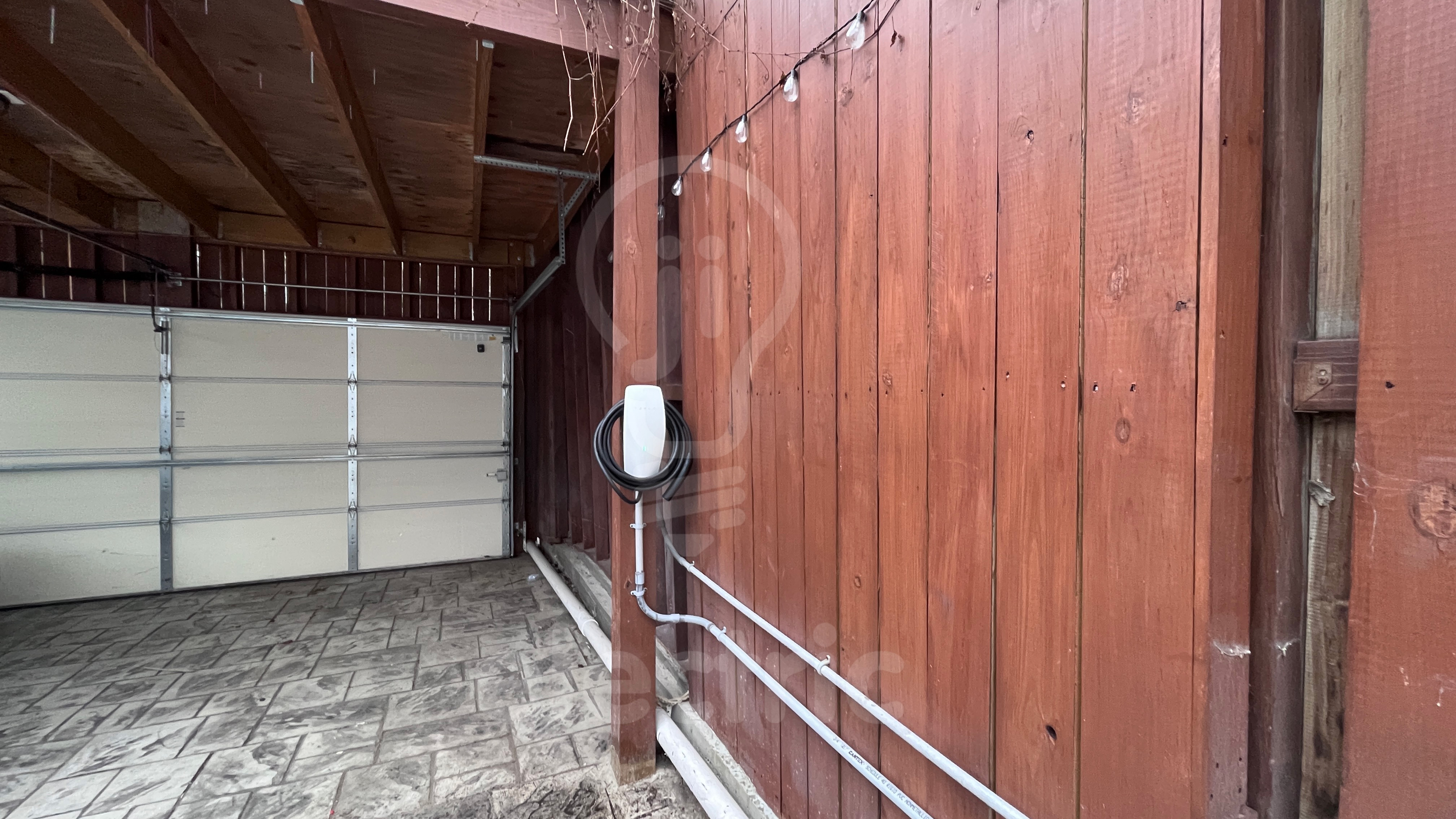 Tesla wall connector in finished garage with racks.